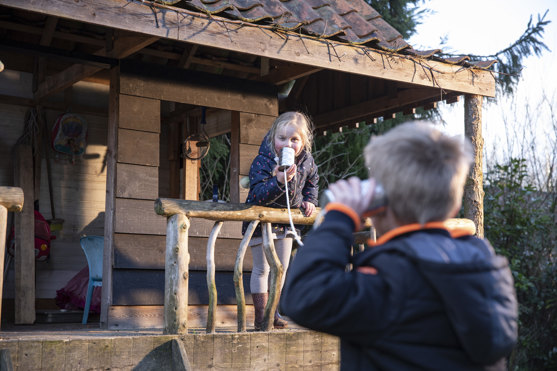 Jongen en meisje bellen elkaar via blikjes en touw