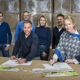 Staand vlnr Maurice Endeman, Alco Liest, Cheryl Jongejan, Romke Hekstra. Joan Veenstra en Sigrid Hoekstra ondertekenen twee puzzelstukken die symbool staan voor de nieuwe samenwerking.