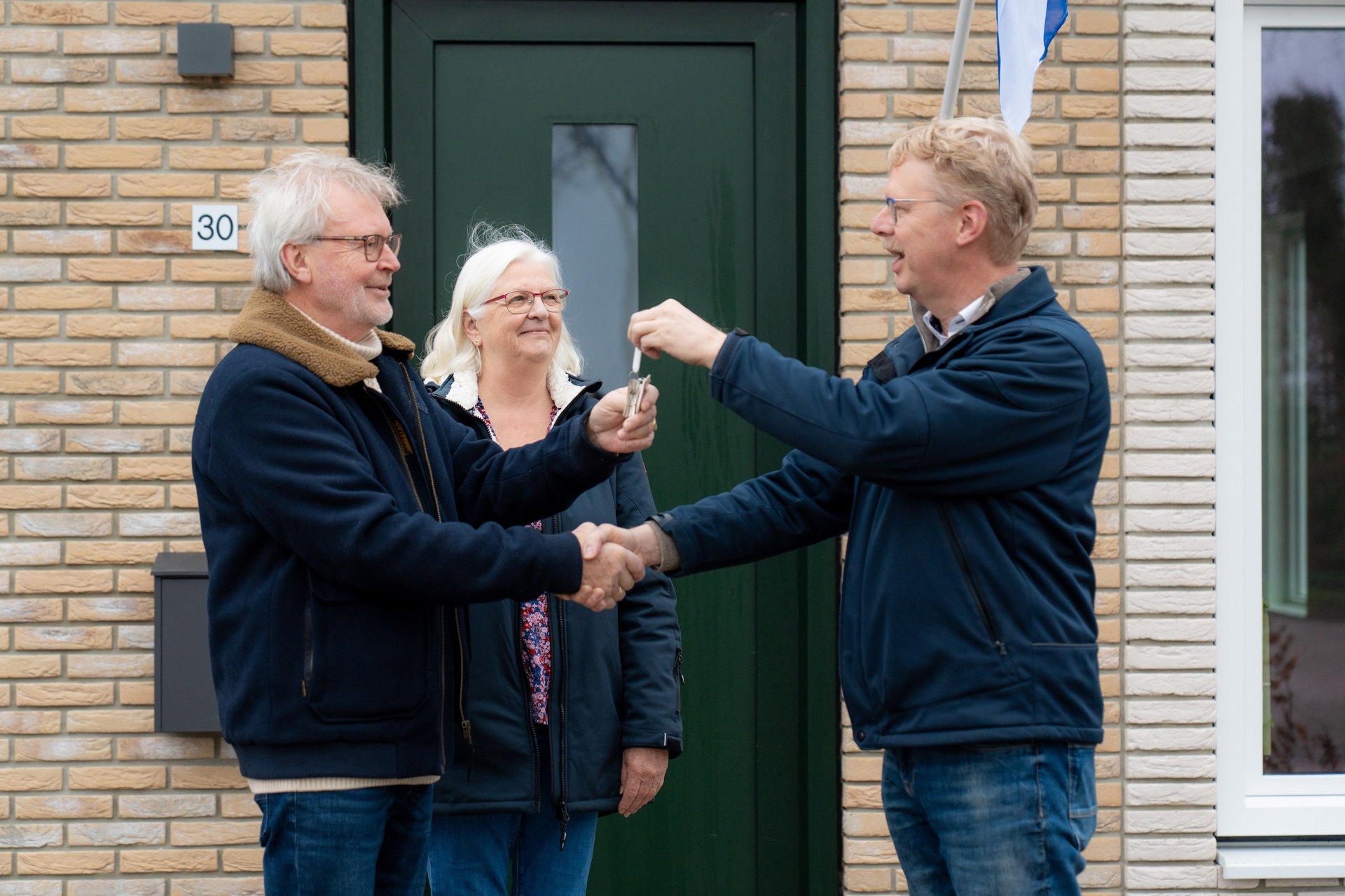 Man en vrouw ontvangen sleutel nieuwe woning