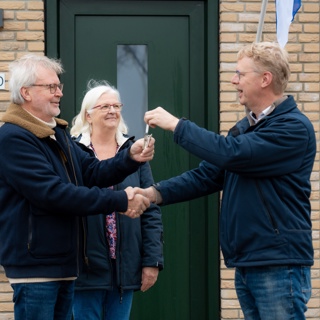 Man en vrouw ontvangen huissleutel van medewerker Corporatie 